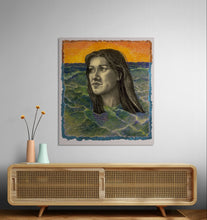 Framed artwork of a woman's face with a sunset and water background on a wall above a wooden console table.