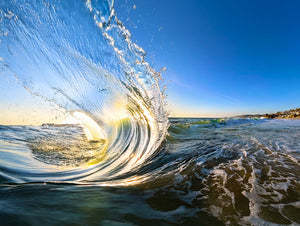 Close-up of a breaking wave with a clear blue sky
