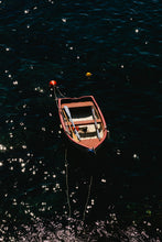 Small boat floating on water at night with stars reflected