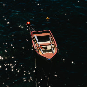 Small boat floating on water at night with stars reflected