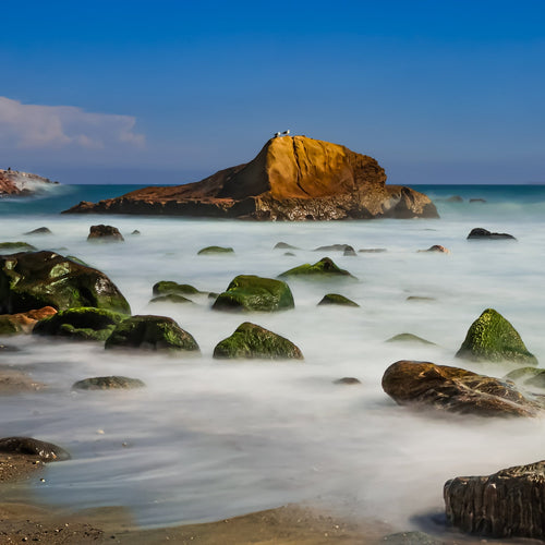 Rocks on a beach with a clear blue sky