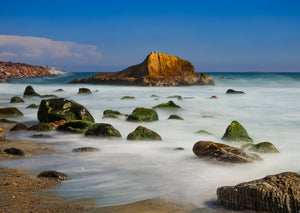 Rocks on a beach with a clear blue sky