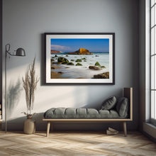 Framed beach photograph on a wall above a sofa in a modern living room.
