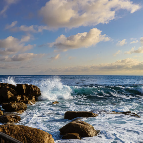 Stairs leading down to a rocky shoreline with waves crashing against the rocks.