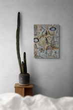 Abstract painting on a wall with a cactus plant on a wooden stand.