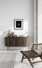 Modern interior with a wooden sideboard, chair, and decorative items against a white wall.