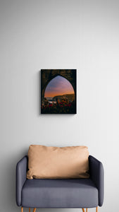 Sofa with a beige pillow against a gray wall with a framed artwork of a sunset landscape.