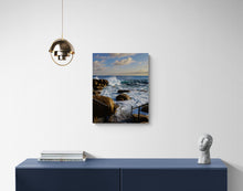 Canvas print of a coastal scene hanging on a wall above a blue console table.