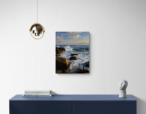 Canvas print of a coastal scene hanging on a wall above a blue console table.