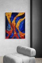 Abstract painting with blue and orange swirls on a gray wall above a gray chair.